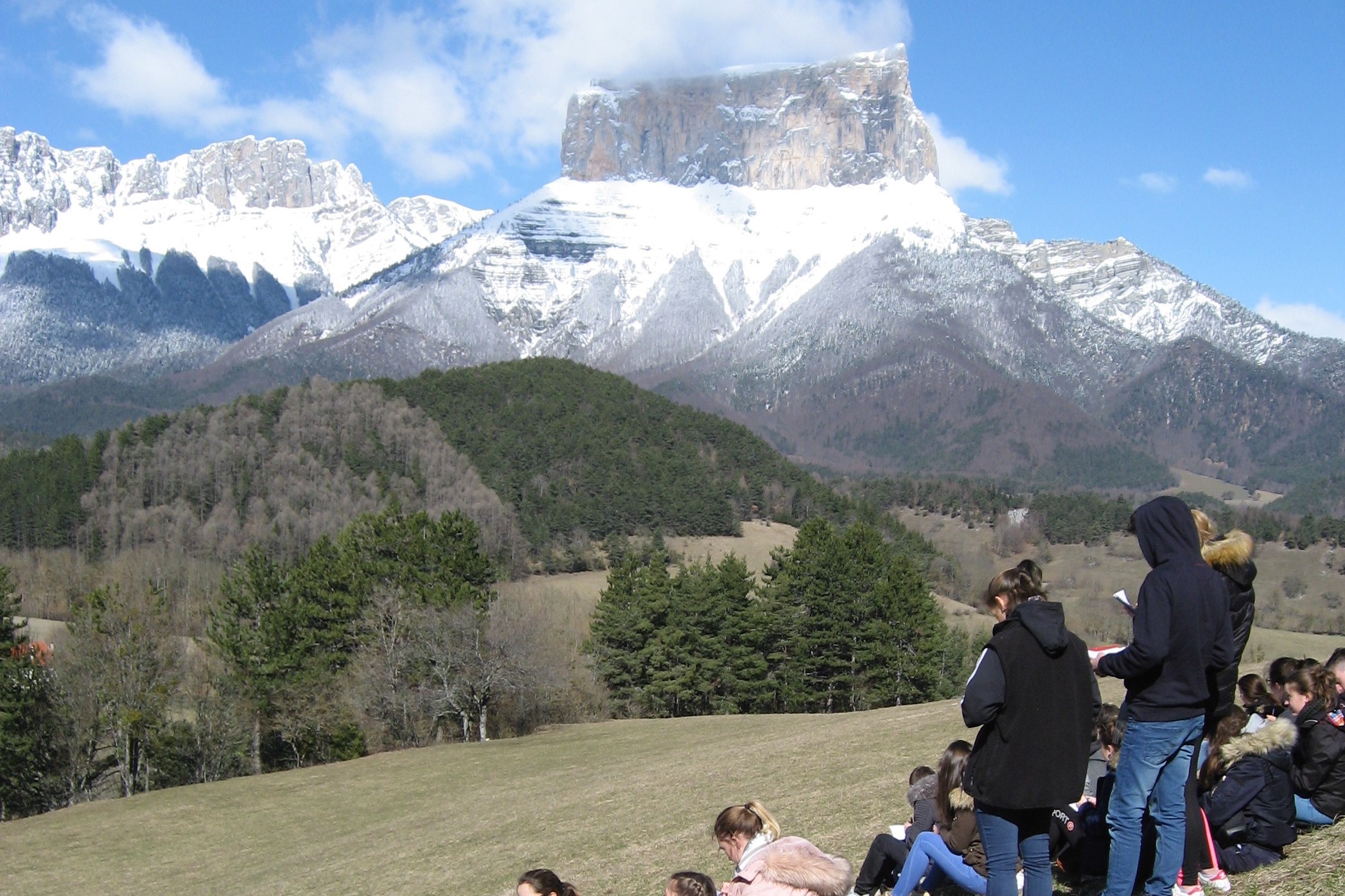 Sortie scolaire d'élèves devant un mont enneigé.