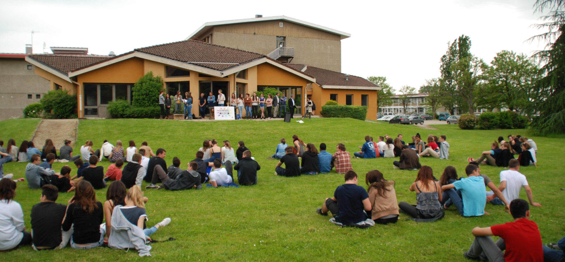 Le lycée agricole vu de l'extérieur avec les apprenants assis dans l'herbe.