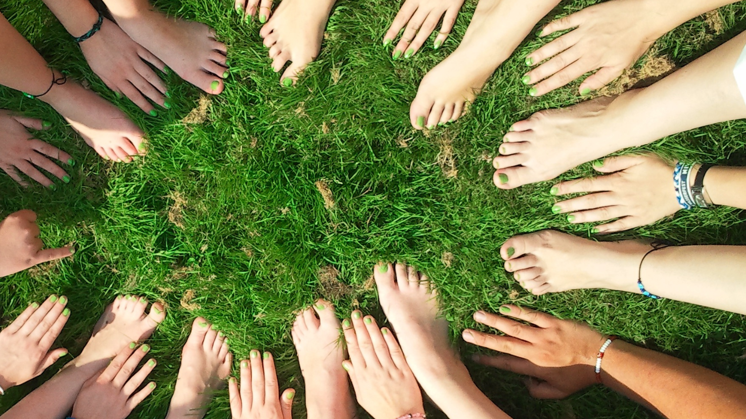 Des mains et des pieds sur la pelouse photographiés d'en-haut.